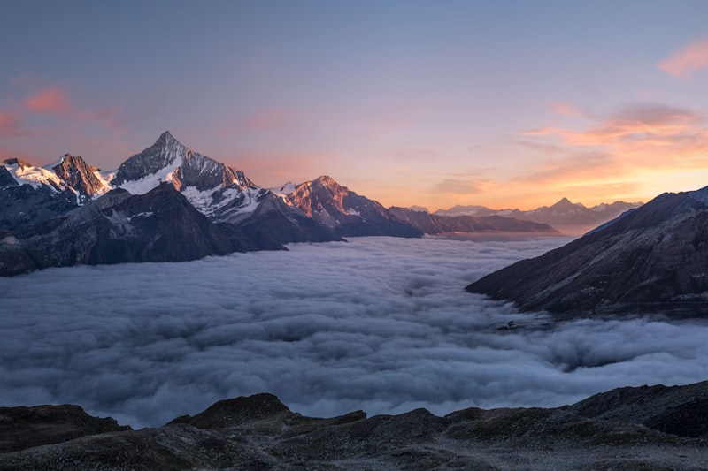 Snow-capped mountain peaks rising above a sea of clouds at golden hour